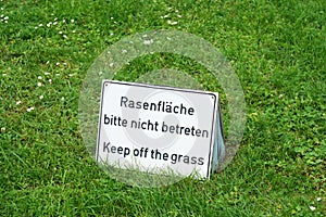 Bilingual keep of the grass sign in Germany photo