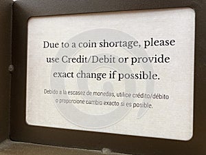 Bilingual sign. Due to a coin shortage, please use credit or debit card or provide the exact