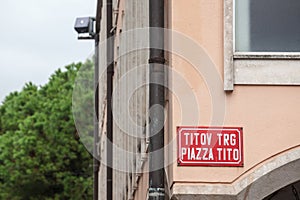 Bilingual street sign indicating Titov Trg in Slovenian and Piazza Tito in Italian,