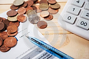 Bill with coins and pen and calculator on table