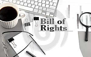 BILL OF RIGHTS text on a paper with magnifier, coffee and keyboard on grey background