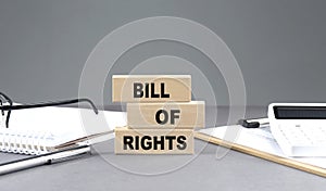 BILL OF RIGHTS text on wooden block with notebook,chart and calculator, grey background