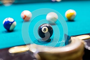 Billiard ball number eight near pocket on blue table