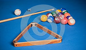 Billiard balls, cue and chalk on a blue pool table.
