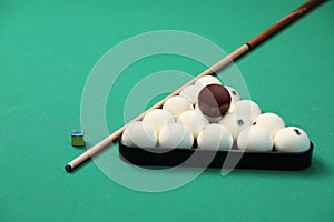 Billiard balls in triangle rack, cue and chalk on table