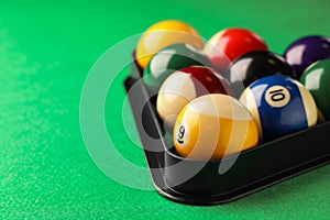 Billiard balls in triangle rack on green table, closeup. Space for text