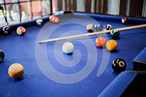Billiard cues and multicolored pool balls on blue billiard table