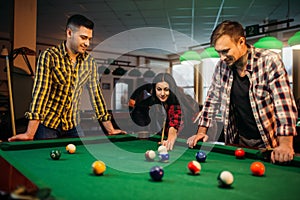 Billiard players with cues at the table with balls