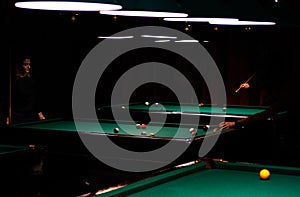 Billiard room with tables and players around them