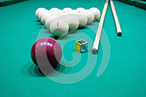 Billiard table with balls, cue and chalk for him