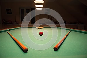 Billiard table with balls and cues in the light of the lamps