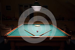 Billiard table with balls and cues in the light of the lamps