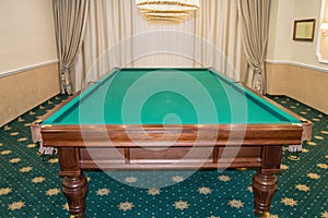 Billiard table with green baize stands in a luxurious living room, a concept of sports and Hobbies for the wealthy