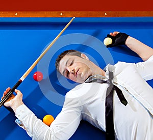 Billiard young man player lying on pool blue table