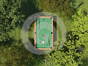 Billiards on the green meadow in the forest among the trees. Single pool table with cue and billiard balls on grass on the top