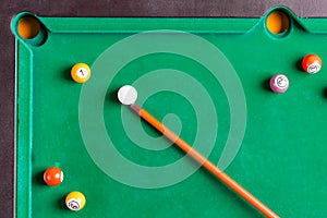 Billiard colorful balls with wooden cue on green table. Snooker, Pool game. Top view.