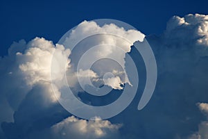 BILLOWING DARK CLOUD WITH PUFFY WHITE CLOUDS IN A BLUE SKY