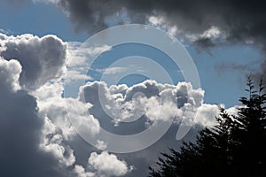 Billowing grey white clouds with blue sky. Stormy weather.