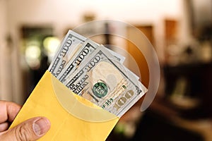 Money - a hand holding an envelope with $100 us dollar bills