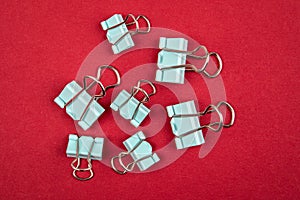 Binder paper clips on a red background. Office supplies