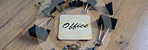 Binder, paperclips on brown table. Office sign