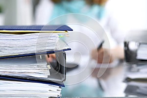 Binders with papers are waiting to be processed with businesswoman or secretary back in blur. Internal Revenue Service