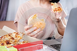 Binge Eating Disorder concept with woman over eating Fast Food Burgers and Pizza photo