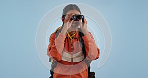 Binocular, backpacker or woman excited, travel or hiking with adventure on a blue studio background. Person, model or