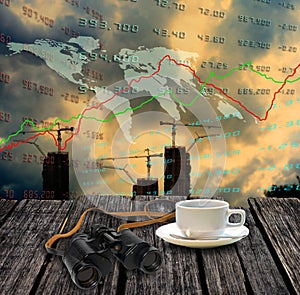 Binocular and coffee cup on table with world stock market data b