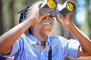 Binocular, search and boy child in a forest for hiking, sightseeing or discovery. Lens, equipment and happy African kid