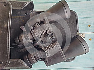 Binoculars in a case on old wooden table, isolated, top view