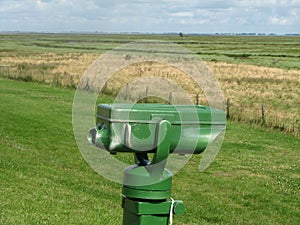 Binoculars at the sea dike in front of a green marsh of the westerschelde sea