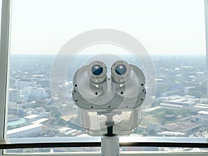 Binoculars for tourist inside the building and city background.