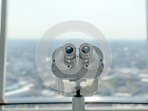 Binoculars for tourist inside the building and city background.