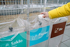 Bins for different garbage. Woman hand throwing a white used crumpled tissue paper handkerchief into a garbage trash bin