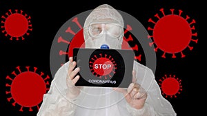 Bio engineer in protective suit and face mask showing tablet pc with sign stop corona virus. Man in protective coat and