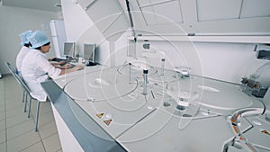 Biochemical analyzer at work with several lab specialist in a pharmaceutical lab.