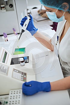 Biochemist using a pipettor for conducting a hematological test