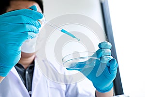 Biochemistry laboratory research, Scientist or medical in lab coat holding test tube with reagent with drop of color liquid over