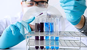 Biochemistry laboratory research, Scientist or medical in lab coat holding test tube with reagent with drop of color liquid over