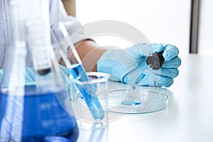 Biochemistry laboratory research, Scientist or medical in lab coat holding test tube with using reagent with drop of color liquid