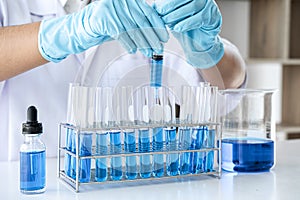 Biochemistry laboratory research, Scientist or medical in lab coat holding test tube with using reagent with drop of color liquid