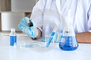 Biochemistry laboratory research, Scientist or medical in lab coat holding test tube with using reagent with drop of color liquid