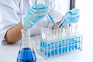 Biochemistry laboratory research, Scientist or medical in lab coat holding test tube with using reagent with drop of color liquid