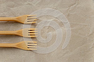 Biodegradable disposable cutlery. Three forks on crumpled brown craft paper background. Concept of zero waste, eco friendly