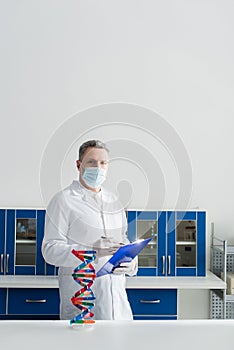 bioengineer in medical mask holding clipboard