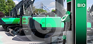 Biofuel filling station on a background of green construction machines. Decarbonization of heavy industrial vehicles photo