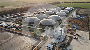 Biogas farm on green fields. Renewable energy from biomass. Modern agricultural biogas plant among beautiful environment