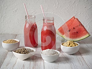 Biological additives superfoods and watermelon smoothie on a white wooden table.