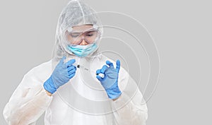 Biological hazard. Epidemic of the Chinese coronavirus. An asian woman in a protective suit and mask holds an injection syringe